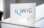 ein Schild mit dem IQWIG Logo auf einem Tagungstisch